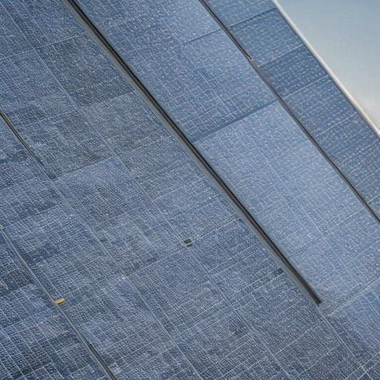 A close-up of several sleek, black-framed solar panels with varying numbers of photovoltaic cells, arranged on a white background, with subtle shadows and soft, natural light.